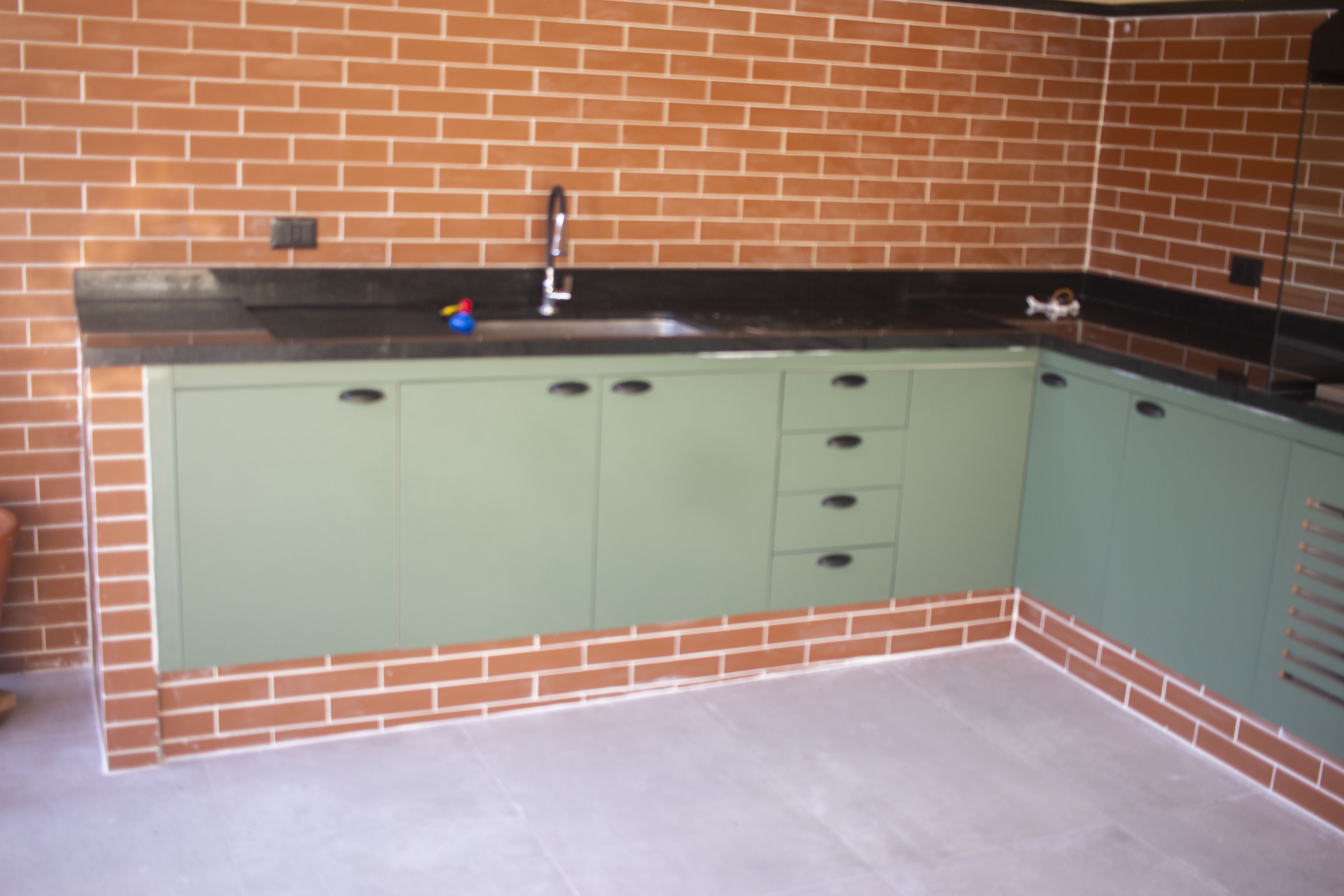 Cozinha planejada verde com bancada em L