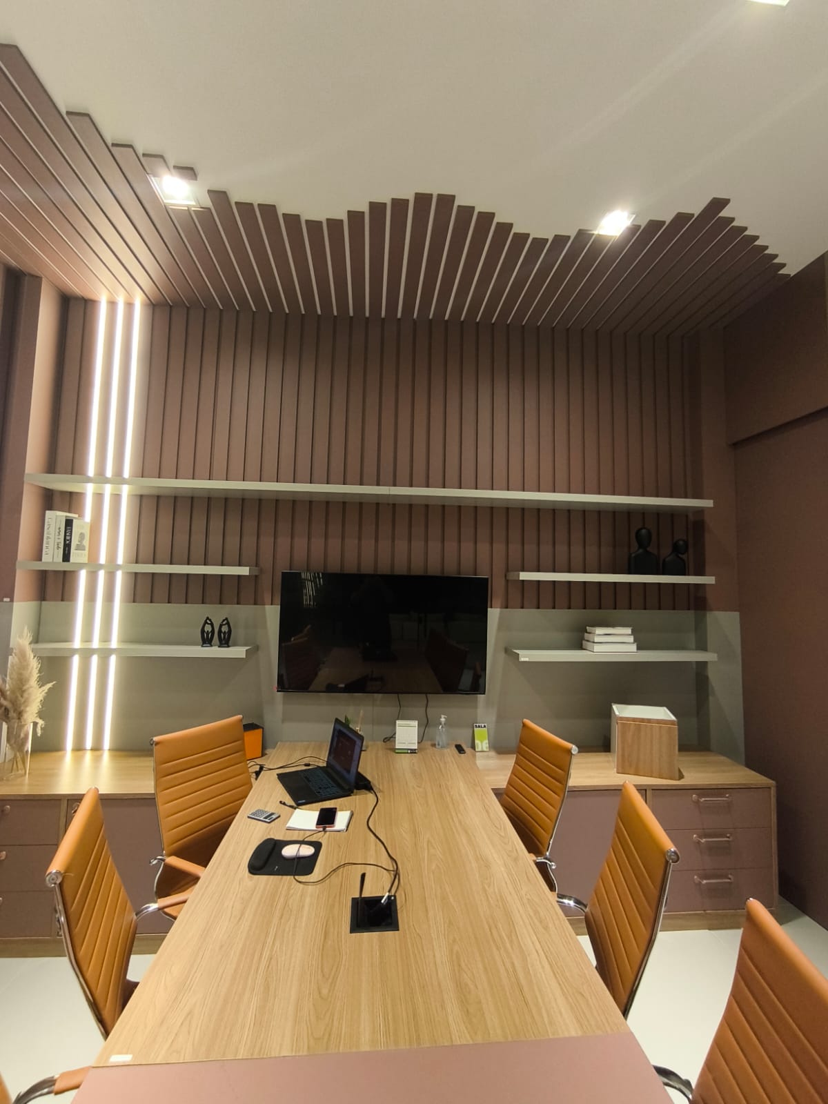 Home office planejado com mesa central e painel ripado